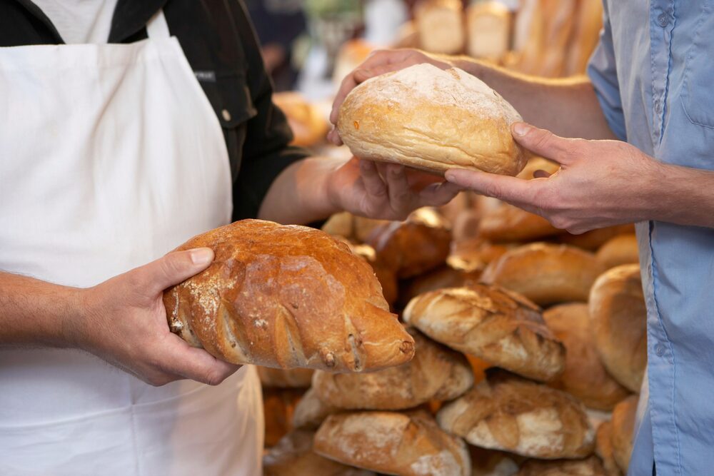 Verkäuferin reicht einem Kunden ein frisches Brot